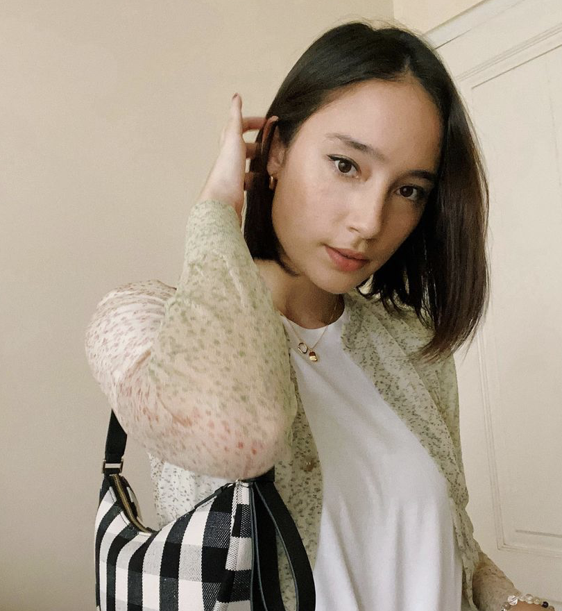 Tatjana is wearing a cardigan and white t-shirt with a bad and a necklace